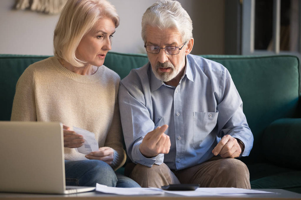 Elderly husband and wife calculate finances paying bills online - Foto, imagen