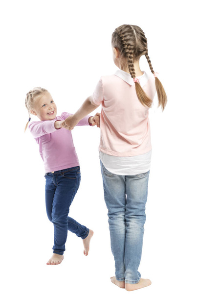 Little girls girlfriends in jeans and pink sweaters hold hands and laugh. Tenderness and friendship. Isolated over white background.  - Zdjęcie, obraz