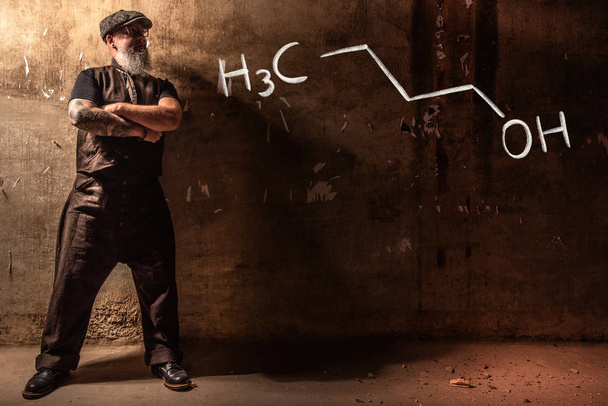 Homem velho barbudo apresentando fórmula química desenhada à mão de n-butanol 1-butanol
 - Foto, Imagem