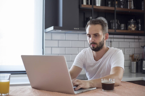 konzentrierter junger Mann, der mit einem Laptop an der Gründung eines kleinen Unternehmens arbeitet. - Foto, Bild