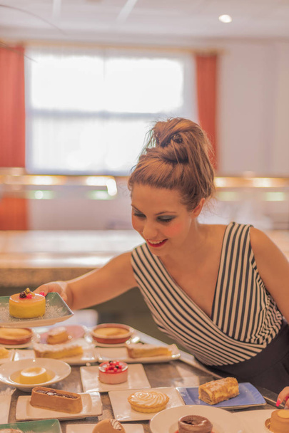 食品ビュッフェでデザートを持つ美しい白人女性 - おいしいデザート - 写真・画像
