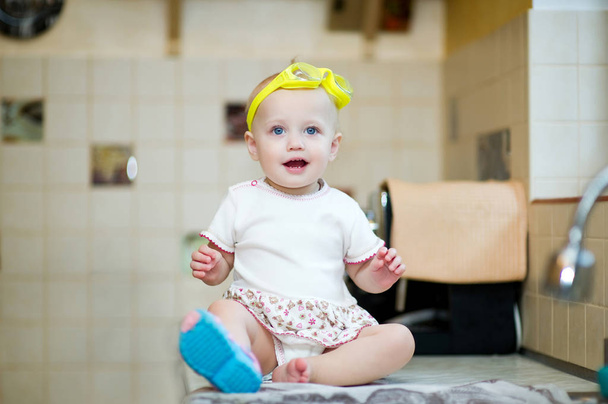 little girl with swimming goggles sits on a kitchen worktop - Zdjęcie, obraz