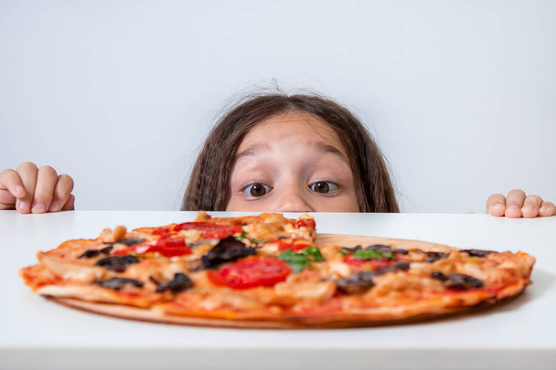 The little girl looks at the pizza. Child found pizza - Photo, image