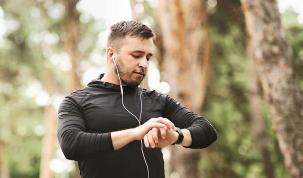 Спортивний чоловік використовує розумний годинник для моніторингу своєї бігової продуктивності
. - Фото, зображення