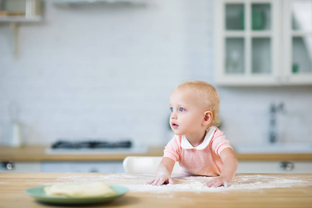pieni vauva tyttö johtaa kätensä työtaso jauhoja ja näyttää pois
 - Valokuva, kuva