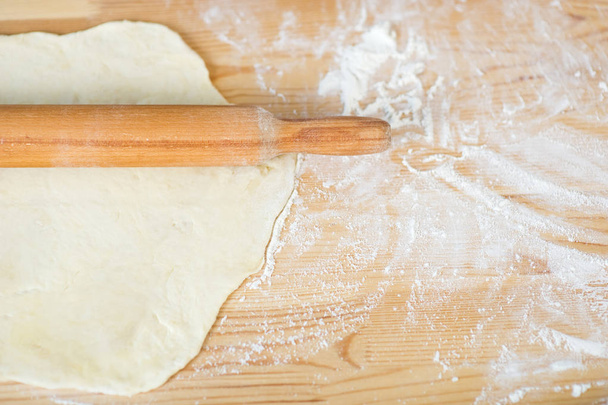 rolling pin and dough lie on a table sprinkled with flour - 写真・画像