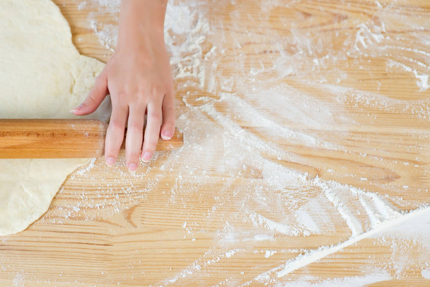 hand, rolling pin for dough, dough, flour and table - Foto, afbeelding