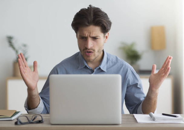Homem chocado olhando para laptop tendo problema em trabalhar em casa
 - Foto, Imagem