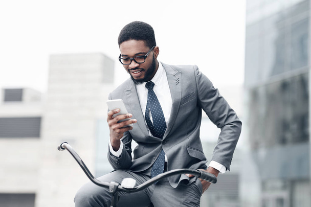 Hombre de negocios guapo usando teléfono inteligente, montando en bicicleta
 - Foto, Imagen