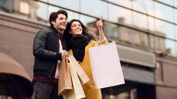 Jeune couple faisant du shopping ensemble dans des boutiques et marchant à l'extérieur
 - Photo, image