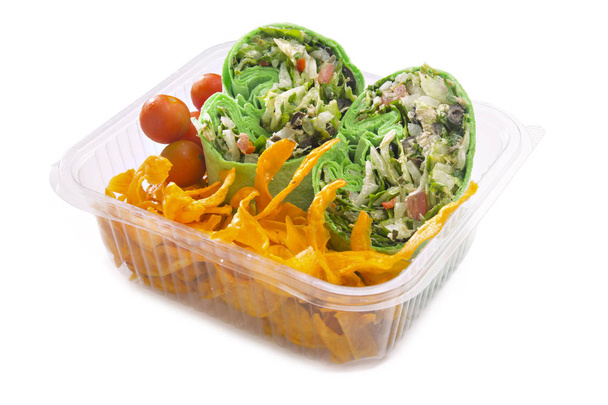Vegetable wraps with cherry tomatoes and sweet potato chips in plastic takeaway container. - Photo, image