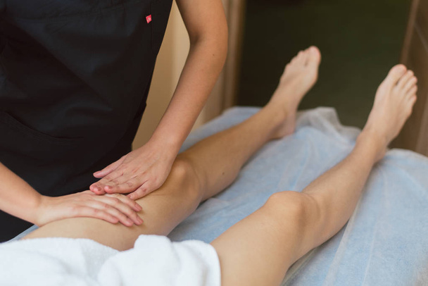 Masajista masajeando la rodilla al joven. El médico masajea la pierna para el tratamiento
 - Foto, Imagen