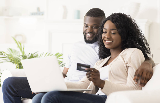 Sorrindo casal africano compras on-line, usando laptop e cartão de crédito
 - Foto, Imagem