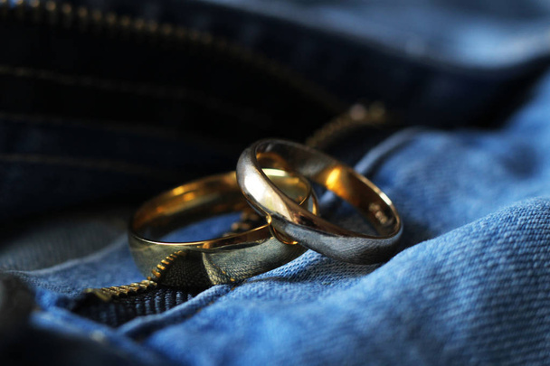 Twee Gouden trouwringen op blauwe jeans. Het begrip liefde of huwelijk. - Foto, afbeelding