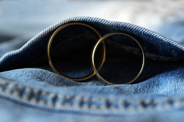 Dwa Złote obrączki na niebieskie dżinsy. Pojęcie miłości lub małżeństwa. - Zdjęcie, obraz