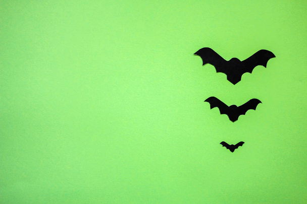 tres murciélagos de papel negro sobre un fondo verde
. - Foto, Imagen