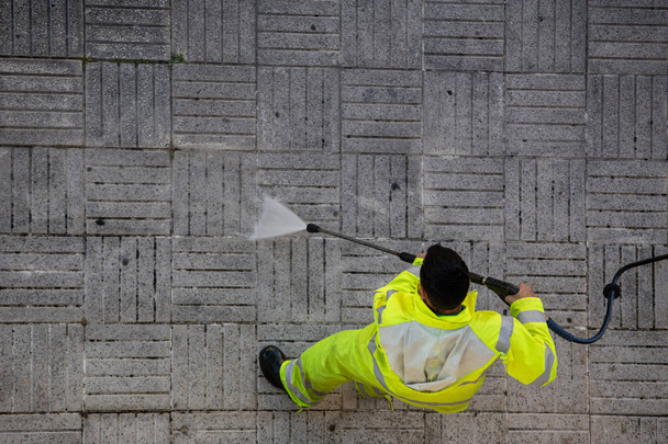 Munkavállaló tisztítása nagynyomású vízsugárral utcai járda - Fotó, kép