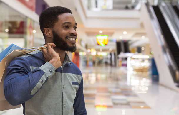 Handsome african guy with paper bags happy after shopping - Foto, Imagem