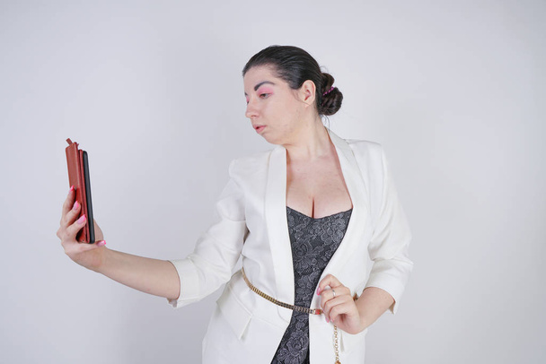 bájos mix faji plusz méretű nőt egy fehér üzleti kabát figyelembe selfie fotó okos telefon a kezében fehér háttér Studio - Fotó, kép