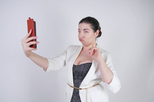 charming mix race plus size woman in a white business jacket do video call with smart phone in hand on white background in Studio - Photo, Image