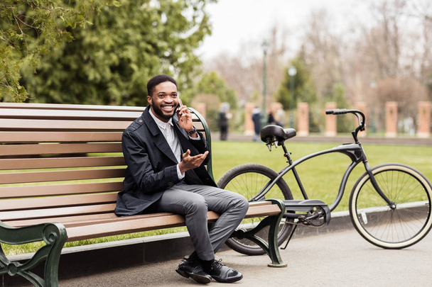 Coffee break. Businessman sitting on bench next to bike - Фото, зображення