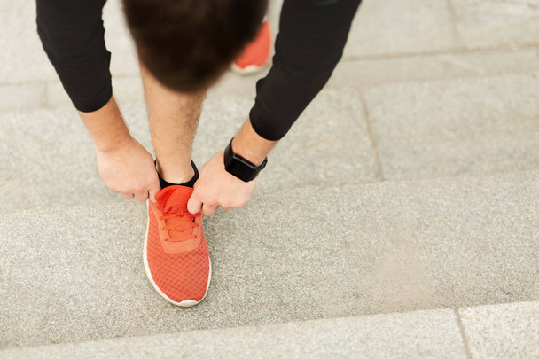 Unrecognizable man tying shoelaces on sneakers before running - 写真・画像