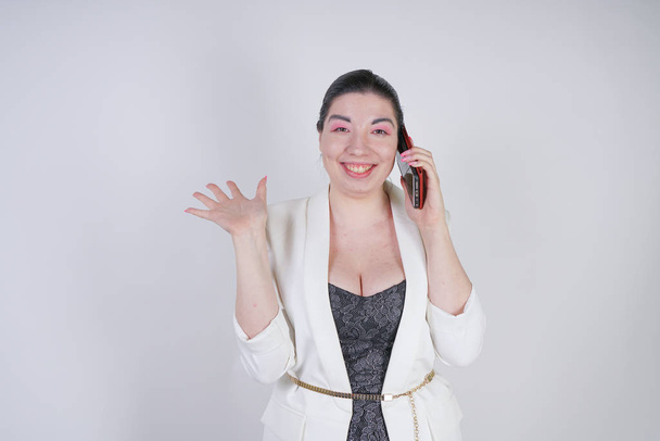 Happy mix Race molett nő egy fehér üzleti dzseki hívó és a beszélő okostelefon a kézben a fehér háttér Studio - Fotó, kép