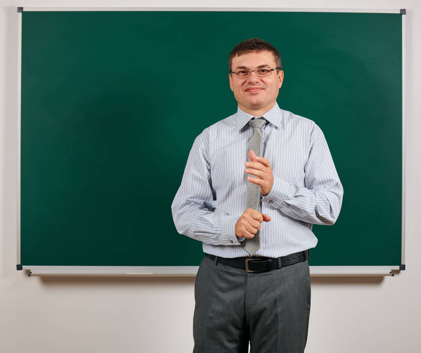 Portrait of a man dressed as a school teacher in business suit, posing at blackboard background - learning and education concept - Photo, Image