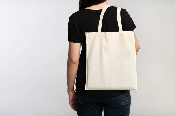 irreconocible chica sosteniendo eco bolsa sobre fondo blanco, vista posterior
 - Foto, imagen