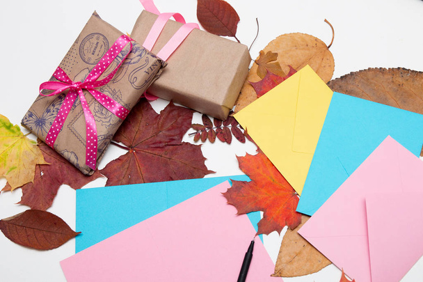 envelopes, cards, thanksgiving gifts, beautiful autumn maple leaves on a white table, copy space. top view, flat lay, ribbons, gift wrapping, send a letter - Φωτογραφία, εικόνα