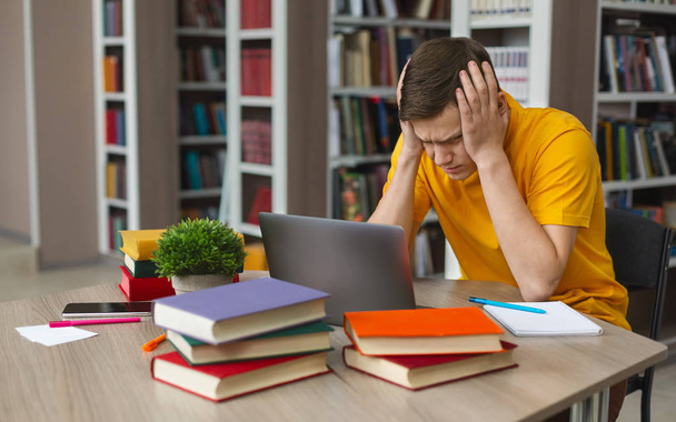 Estudiante cansado sentado frente a la computadora portátil, apretando la cabeza
 - Foto, Imagen