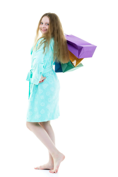Cheerful girl in a short robe waving multicolored paper bags. Th - Фото, изображение