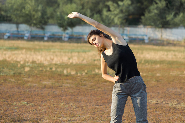 Una joven chica atlética delgada en ropa deportiva con estampados de piel de serpiente realiza un conjunto de ejercicios
. - Foto, Imagen