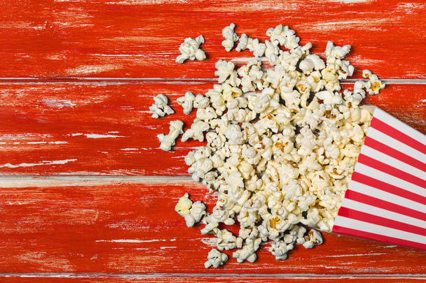 Popcorn emmer op rode houten achtergrond met kopieerruimte. Bovenaanzicht. Vlakke plaat - Foto, afbeelding