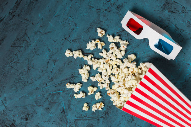 Wiadro popcornu i okulary 3D z miejscem na ksero na niebieskim tle teksturowanym. Widok góry. Układy płaskie - Zdjęcie, obraz