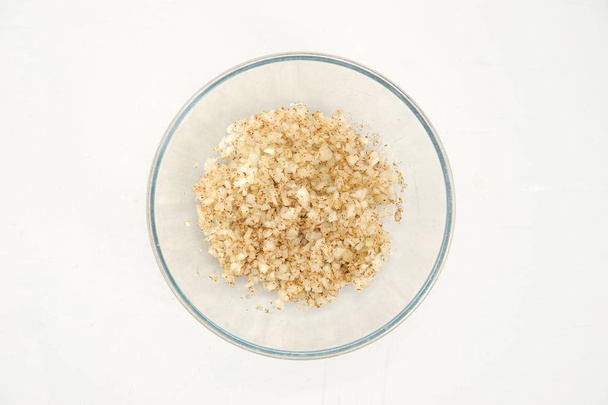 In a deep bowl, the onion, mixed with spices. White background. Close-up. View from above. - Foto, afbeelding