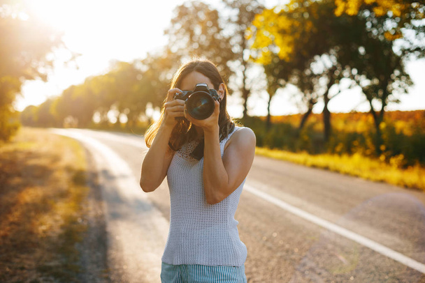 Foto van jonge vrouw, het nemen van foto, reiziger concept, zon lichten - Foto, afbeelding