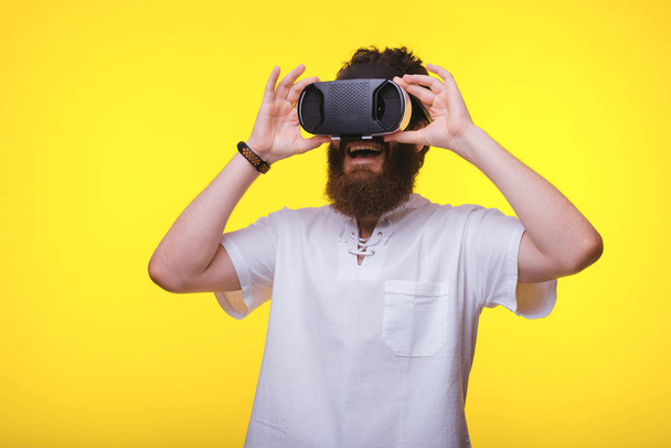 Όμορφος μουσάτος άνθρωπος, με γυαλιά VR, πάνω από κίτρινο φόντο - Φωτογραφία, εικόνα