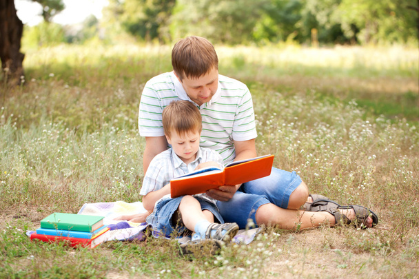 Isä ja poika lukemassa yhdessä
 - Valokuva, kuva