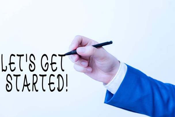 Text sign showing Let S Get Started. Conceptual photo encouraging someone to begin doing something Isolated hand above white background. Pointing pen in the hand on white background. - Photo, Image