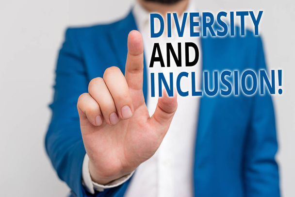 Woord schrifttekst diversiteit en inclusie. Business concept voor Range huanalysis verschil omvat ras etniciteit gender zakenman in blauwe suite en wit overhemd wijzend met vinger in lege ruimte - Foto, afbeelding