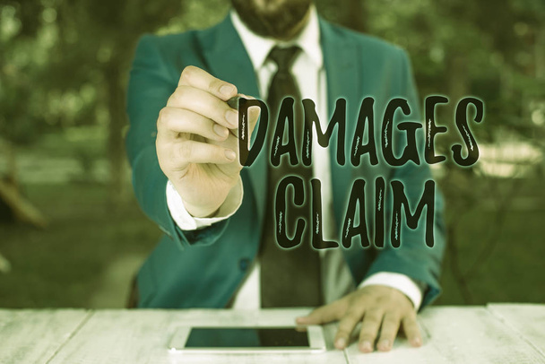 Writing note showing Damages Claim. Business photo showcasing Deanalysisd Compensation Litigate Insurance File Suit Businessman holds pen and points into copy space. - Photo, Image