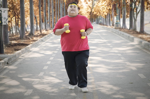 Overweight man jogging at autumn park - Foto, afbeelding