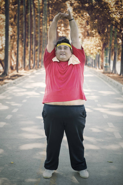 Young fat man looks tired after exercises on studio - 写真・画像