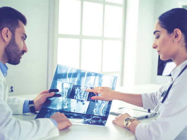 Two doctors studying x-ray image, consulting in bright office - Photo, Image