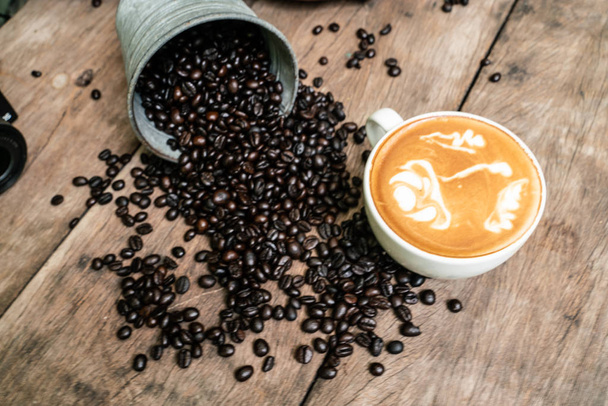 Filiżanka kawy latte art z ziaren kawy na drewnianym stole - Zdjęcie, obraz