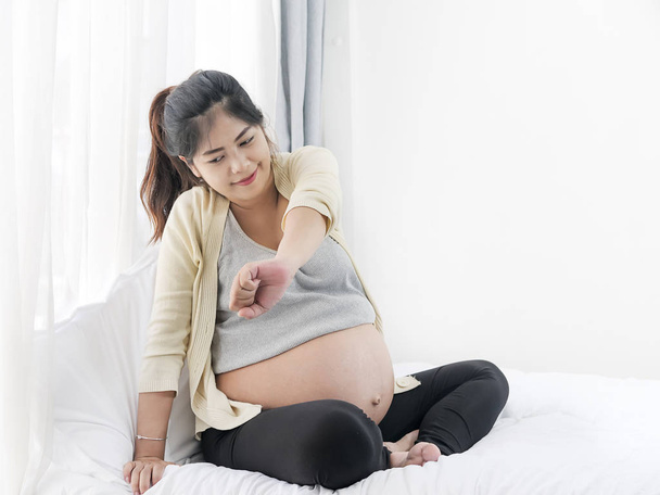 Pregnant Asian woman with back pain in front of a window, health - Foto, afbeelding