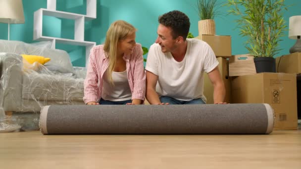 A fiatal párok egy szőnyeget takarnak, és új lakásban fekteti le - Felvétel, videó