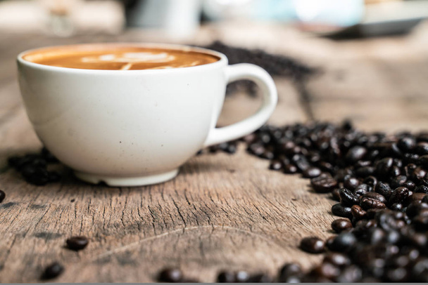 Latte art coffee cup with coffee bean on wood table - Φωτογραφία, εικόνα