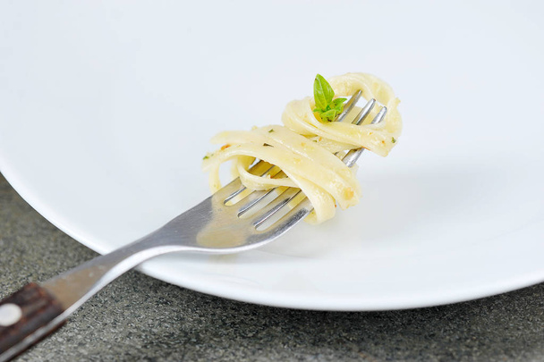 Pasta with pesto on a fork. Close-up. Macro shot. Light background. - Zdjęcie, obraz